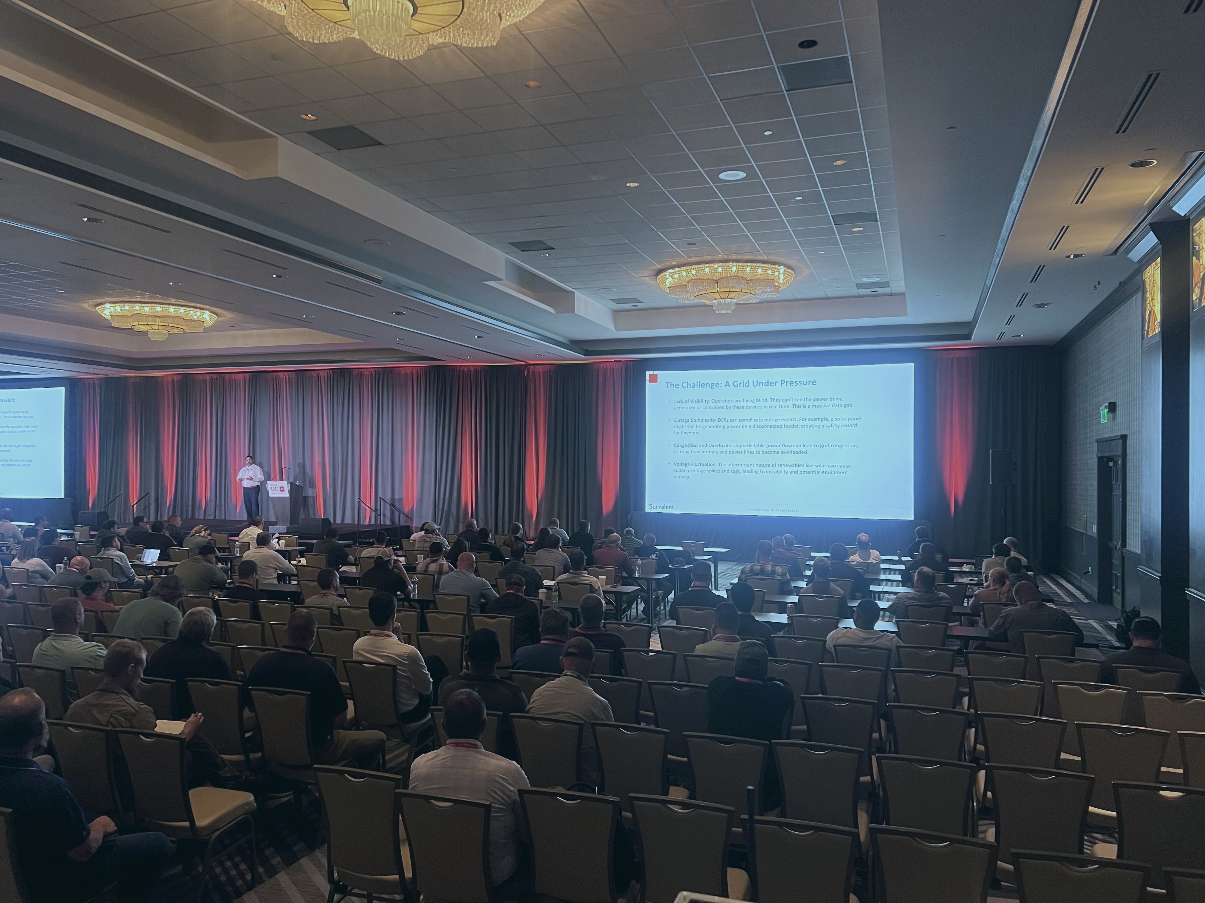 Corporate conference room with stage, projection, lighting, and audience.